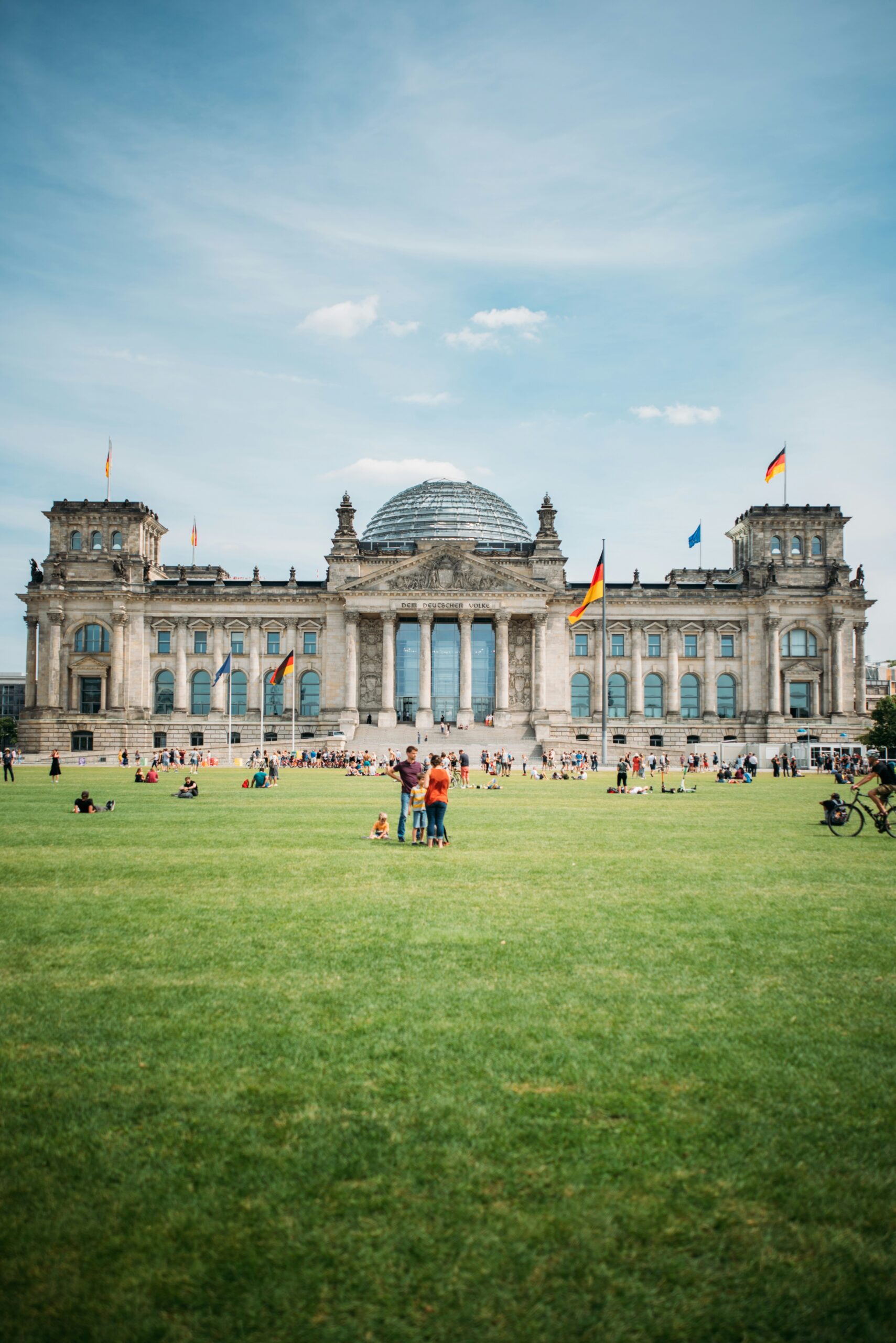 Menschen die auf der grünen Wiese vor dem Bundestag stehen