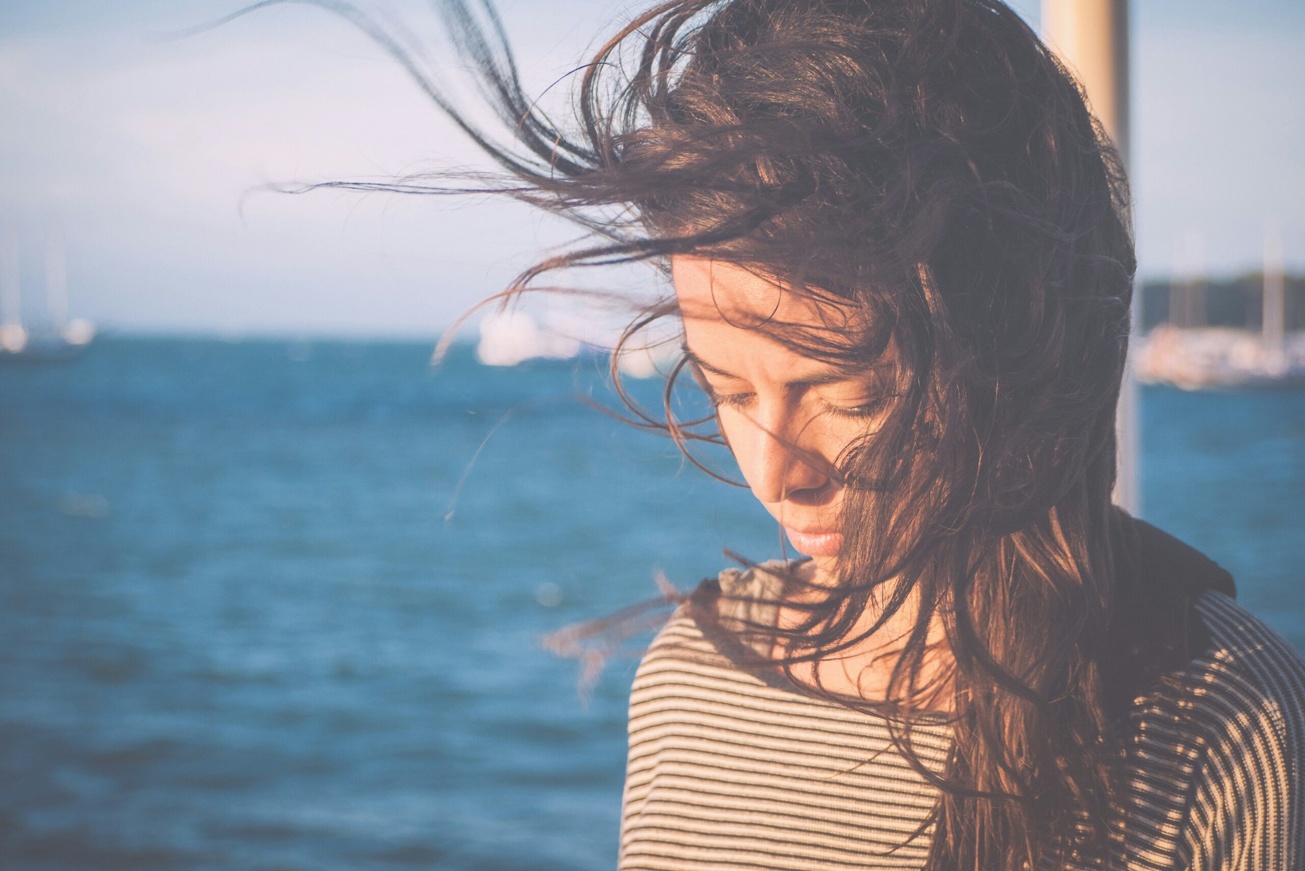 Frau mit wehenden Haaren vor Wasser